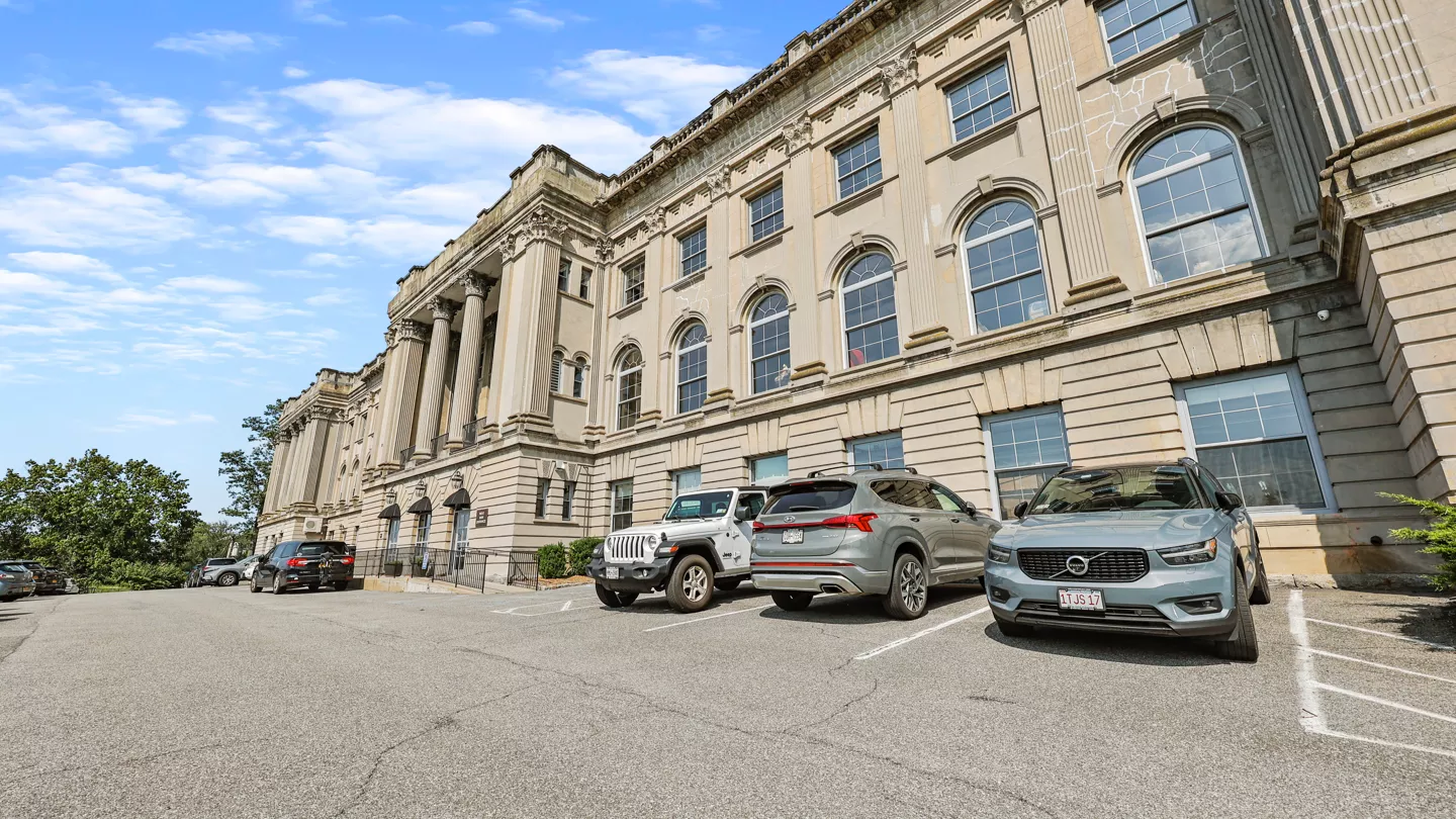 An interior view of The Cosmopolitan, showcasing a workspace with brick walls. A window offers a view of the Hudson River, bringing natural light into the room and providing a tranquil setting.